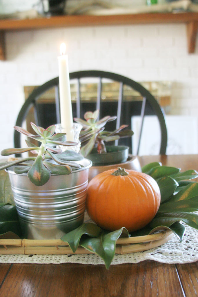 A simple fall centerpiece with pumpkins, magnolia leaves and succulents. #Thanksgiving #Tablescape