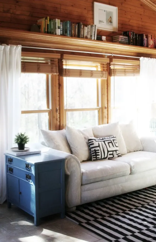 Sunroom makeover progress with wood paneling, white curtains, white furniture, black and green details. Light & Bright Eclectic Home Tour by @CraftivityD