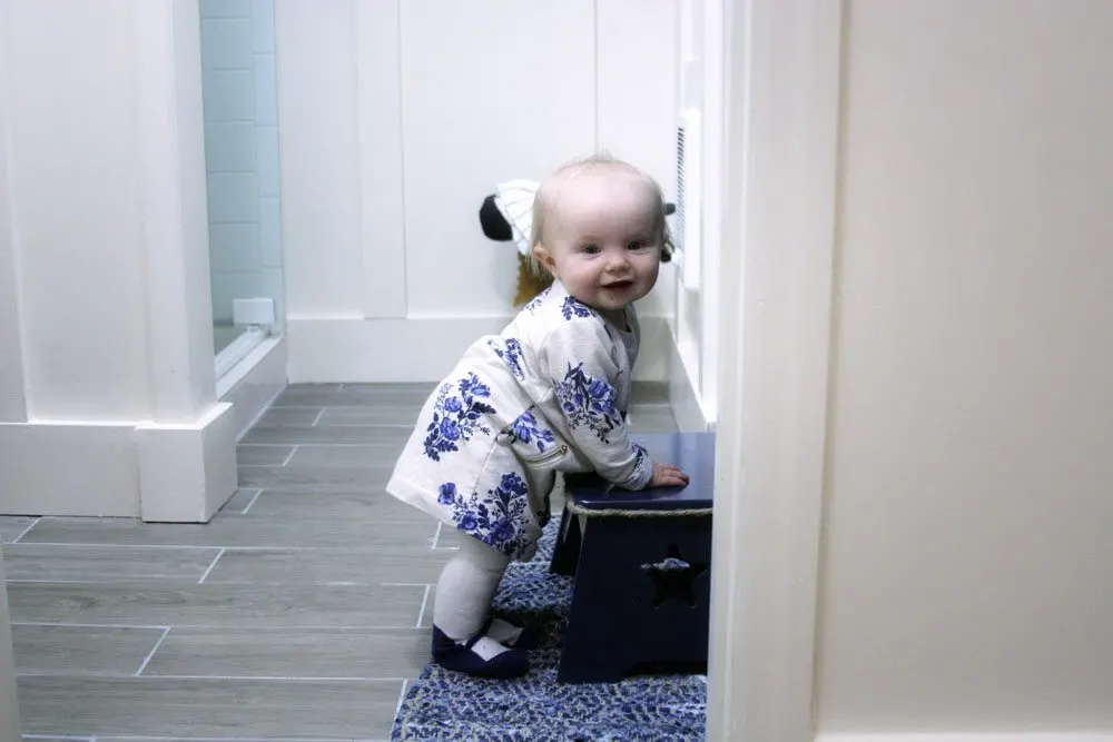 Little girl holding onto a bathroom stool. 