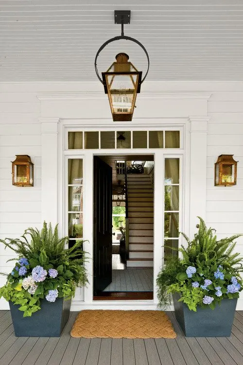 Home with white siding, a black front door idea, and blue planters