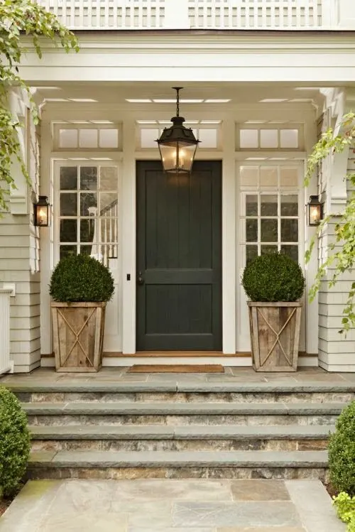 White home with wooden planters and a charcoal front door idea