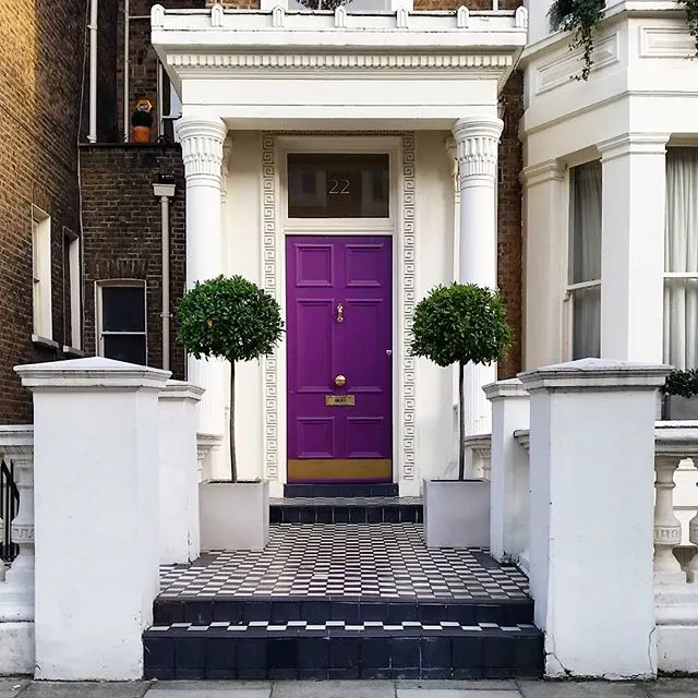 White and brick home exterior with a deep purple front door idea