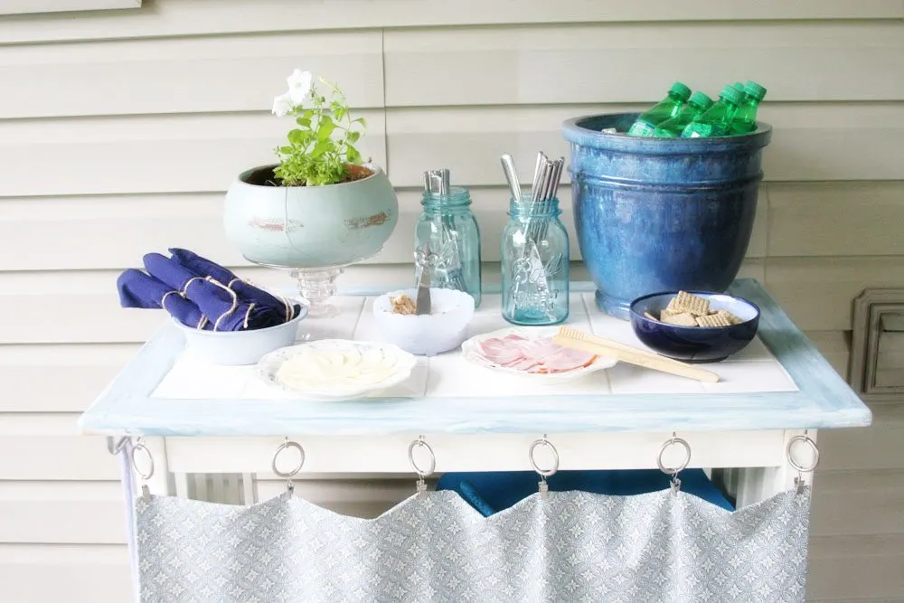 DIY outdoor serving bar with food, drinks, and utensils. 