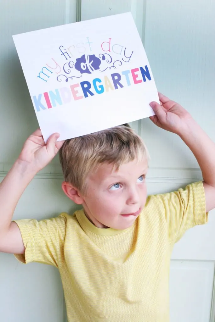 Boy holding a sign that says "my first day of kindergarten" 