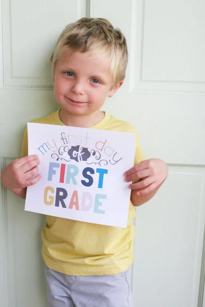 Boy with a printable sign reading "my first day of first grade"