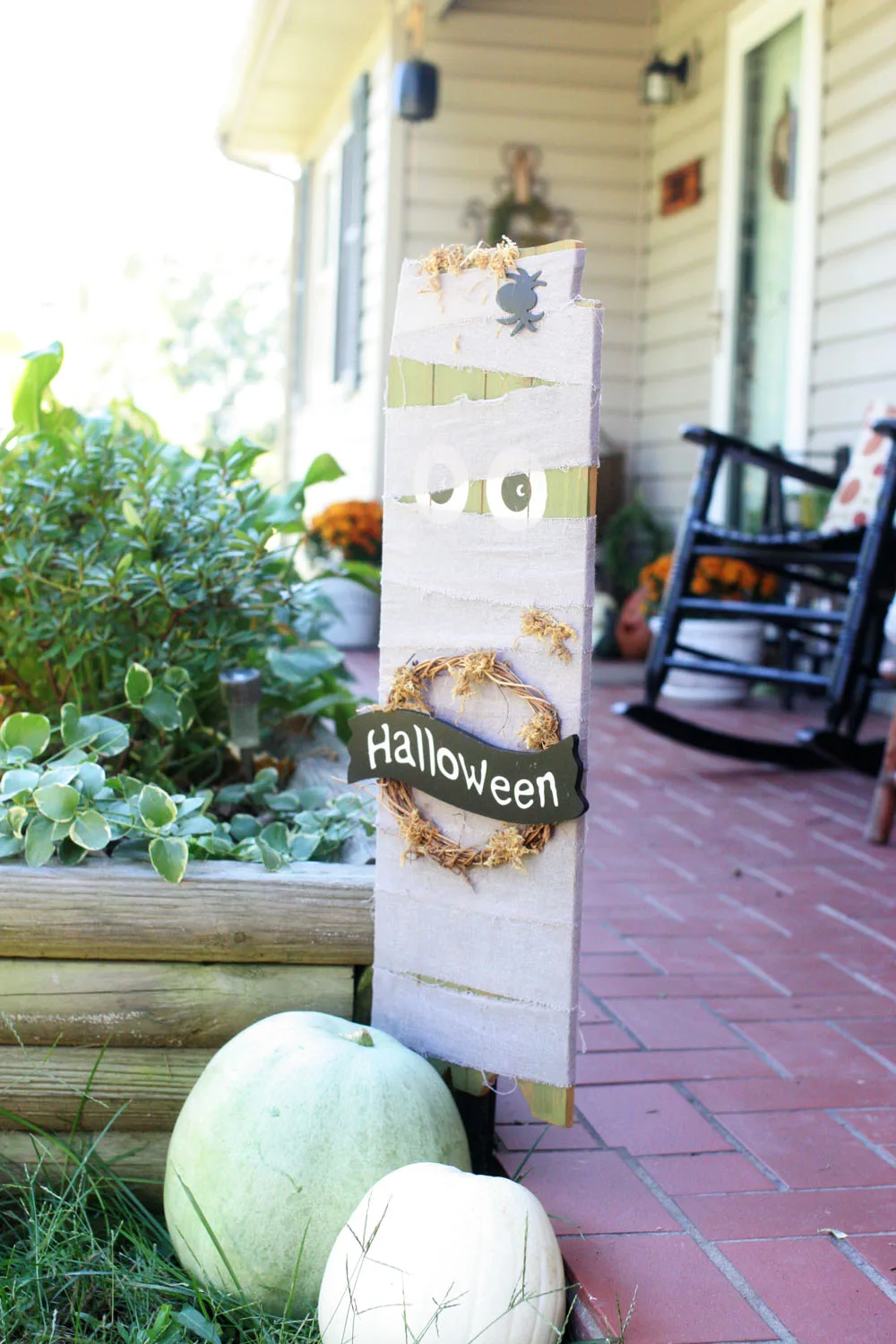 Cute pumpkin display and wooden mummy sign used as DIY outdoor Halloween decorations