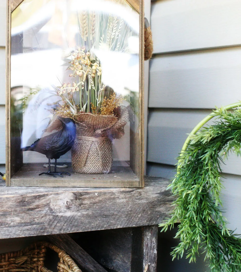 A fall flower arrangement and crow figurine used as DIY outdoor Halloween decorations.