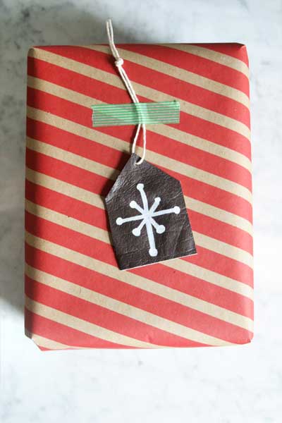 Leather Scrap Gift Tags in Minutes A red and kraft striped wrapped parcel with a dark leather gift tag hand painted with a white snowflake