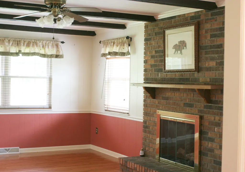 dining room BEFORE with dark brick fireplace and coral walls