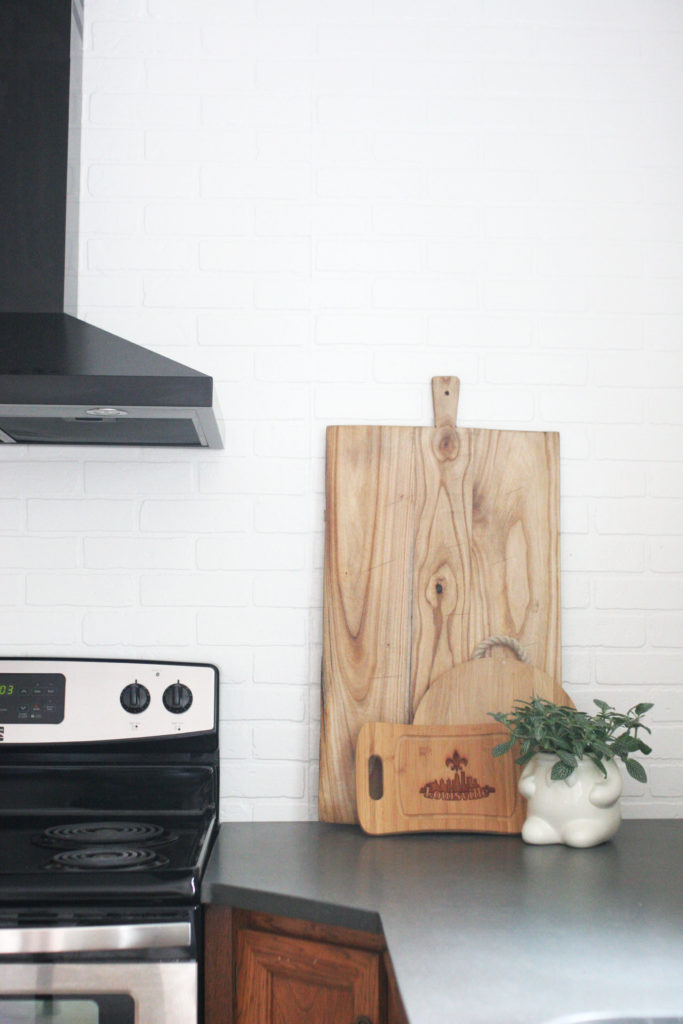 blank range hood, brick backsplash, bread boards