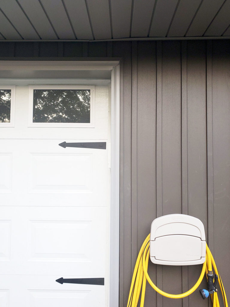 Dark Gray Board and Batten Siding (Vertical Siding), White Garage Door, and Water Hose Storage