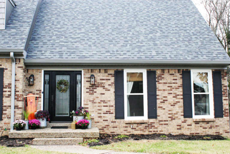 A Modern Christmas Cottage with a Brick Exterior, Black Front Door, Black Shutters, and Gray Siding