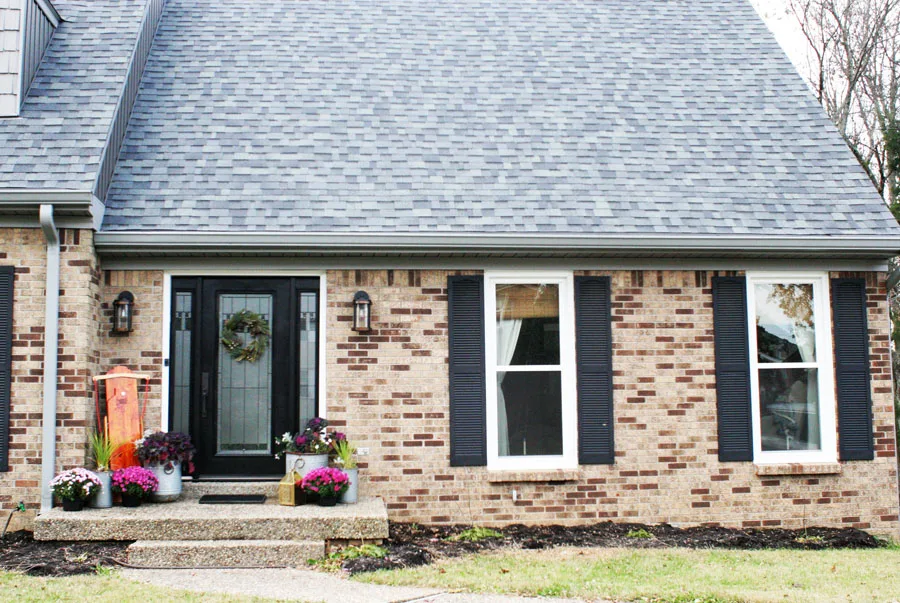 A Modern Christmas Cottage with a Brick Exterior, Black Front Door, Black Shutters, and Gray Siding 