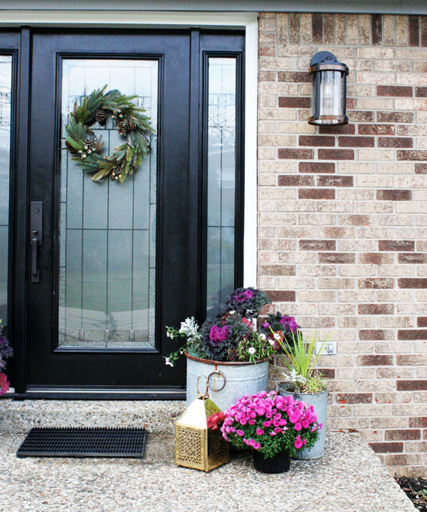 Black Front Door with Christmas Wreath and Pink Flowers in Planters.