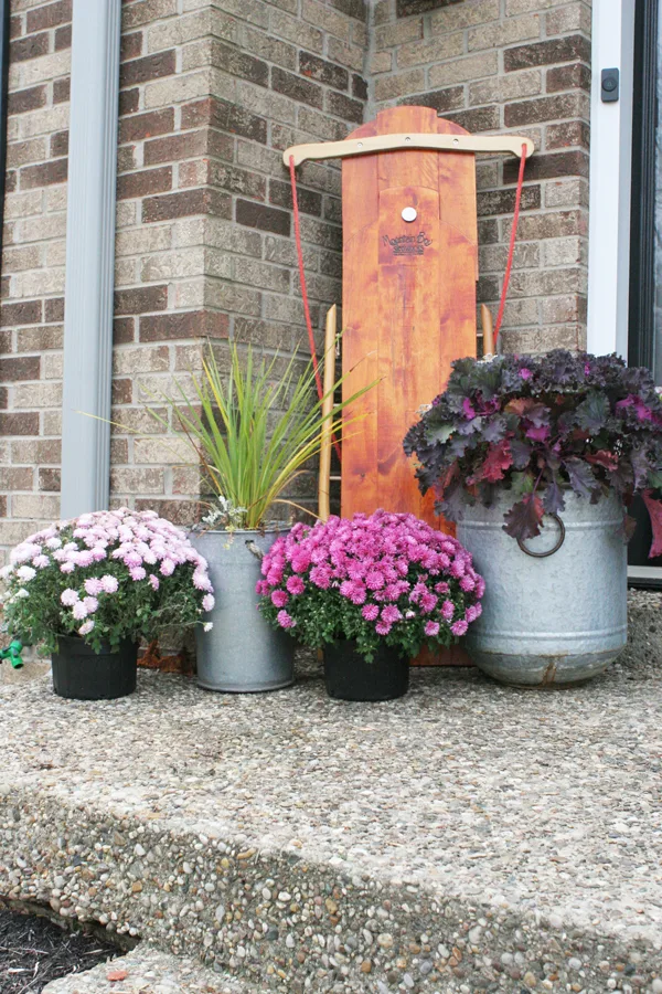 Christmas Porch Decorations include a Wood Sled and Pink Flowers in Planters