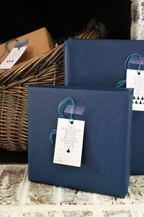 Presents wrapped in Navy Gift Wrap with Black and White Modern Gift Tags, sitting on a white brick hearth.