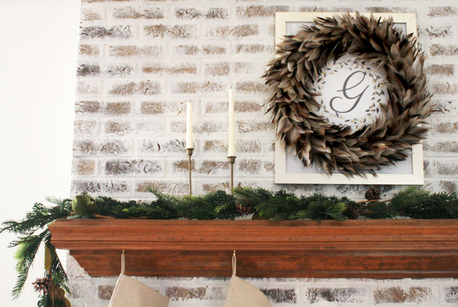 Fireplace Christmas Decorations with Feather Wreath, Brass Candles, and Garland. Christmas Mantel Ideas on a German Schmear Brick Fireplace.