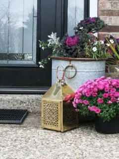 Christmas front porch decor with a brass lantern and pink flowers
