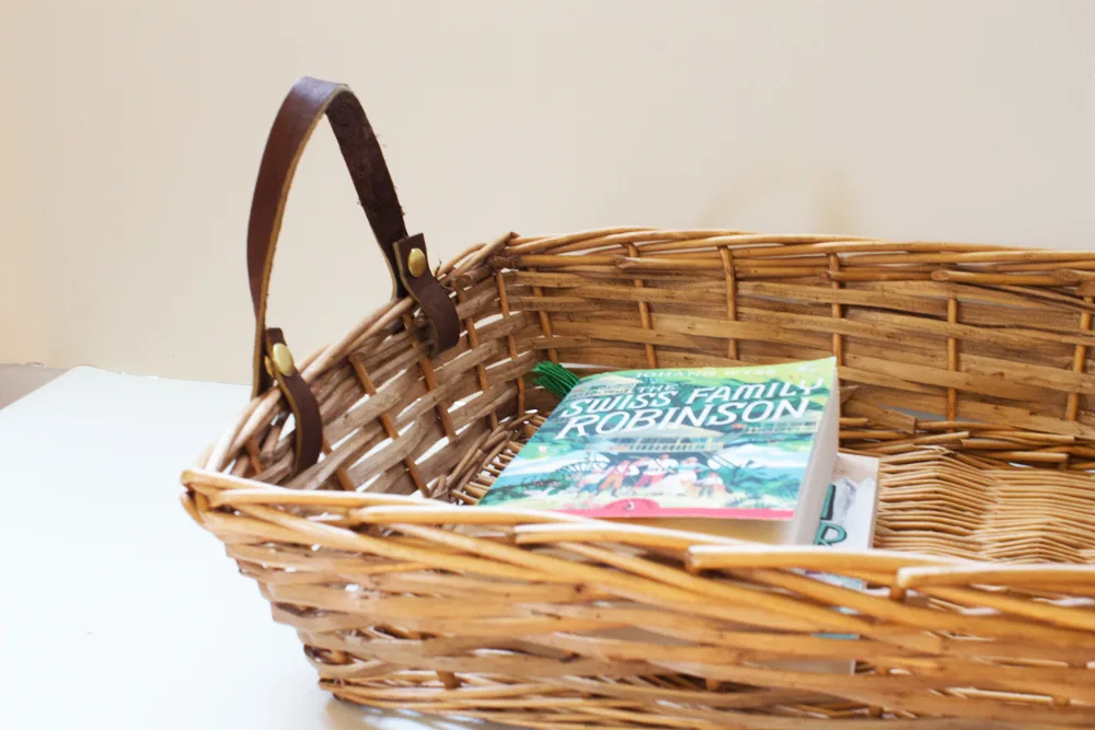 wicker basket with leather handles holding library books