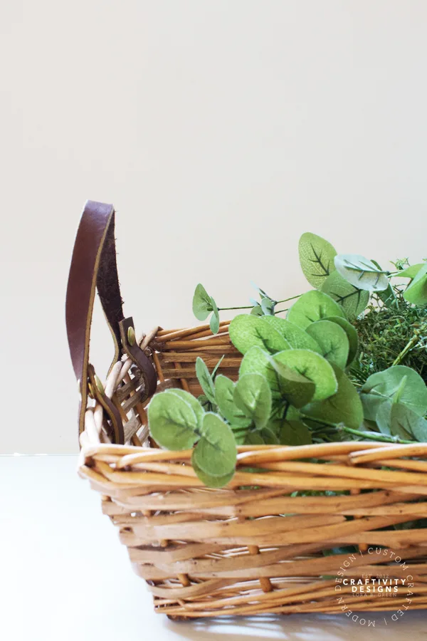 leather handles on a wicker basket filled with greenery