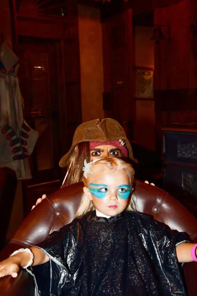 Captain Jack Sparrow peaking over preschooler getting mermaid makeover at the Pirates League.