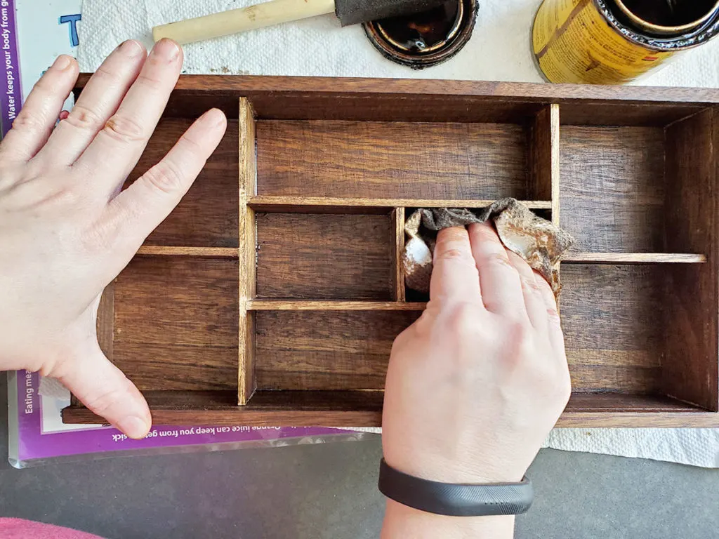 Wipe away wood stain with paper towel to finish the DIY essential oil shelf