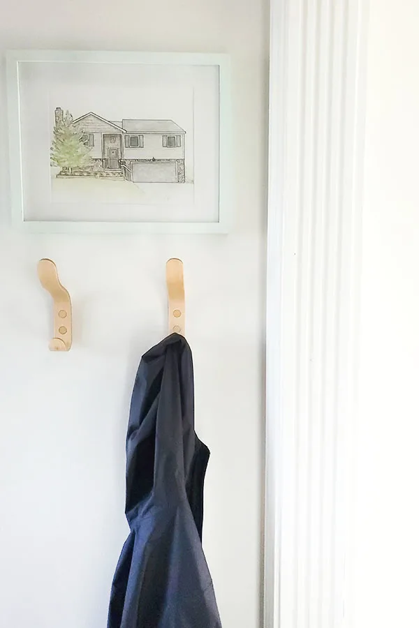 Entryway with modern maple coat hooks and watercolor house painting