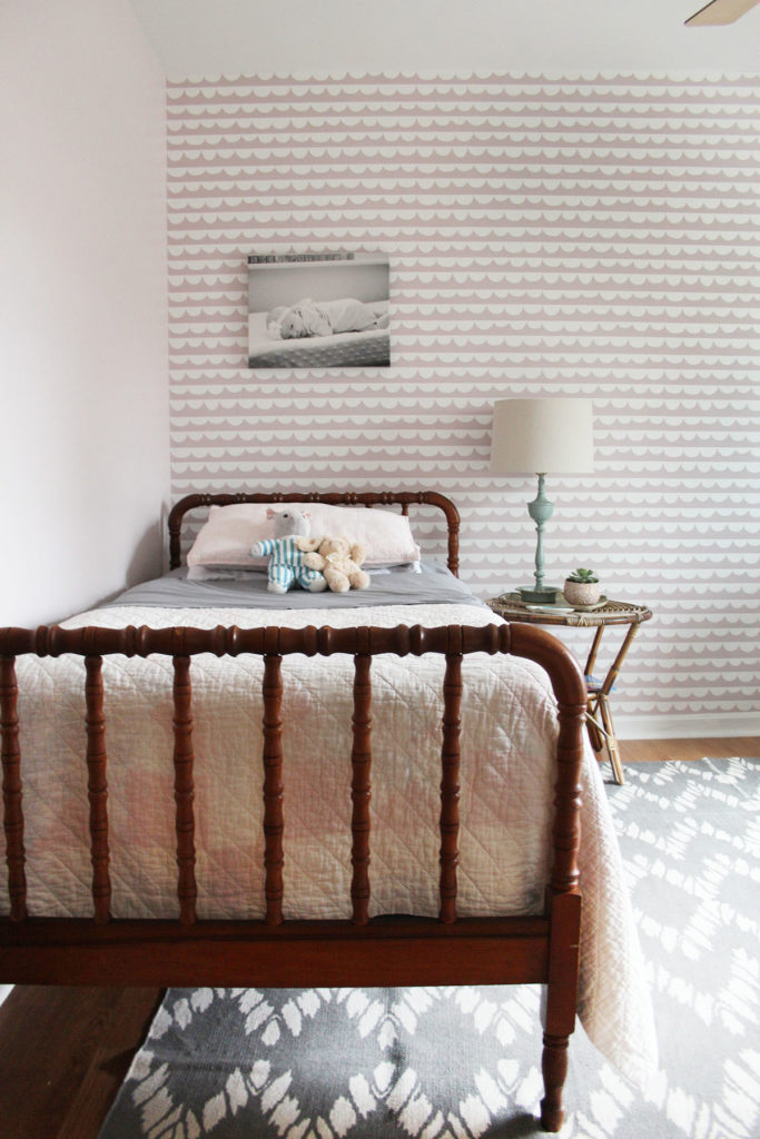 Pink wallpaper in a girls room with a Jenny Lind Bed and gray rug.