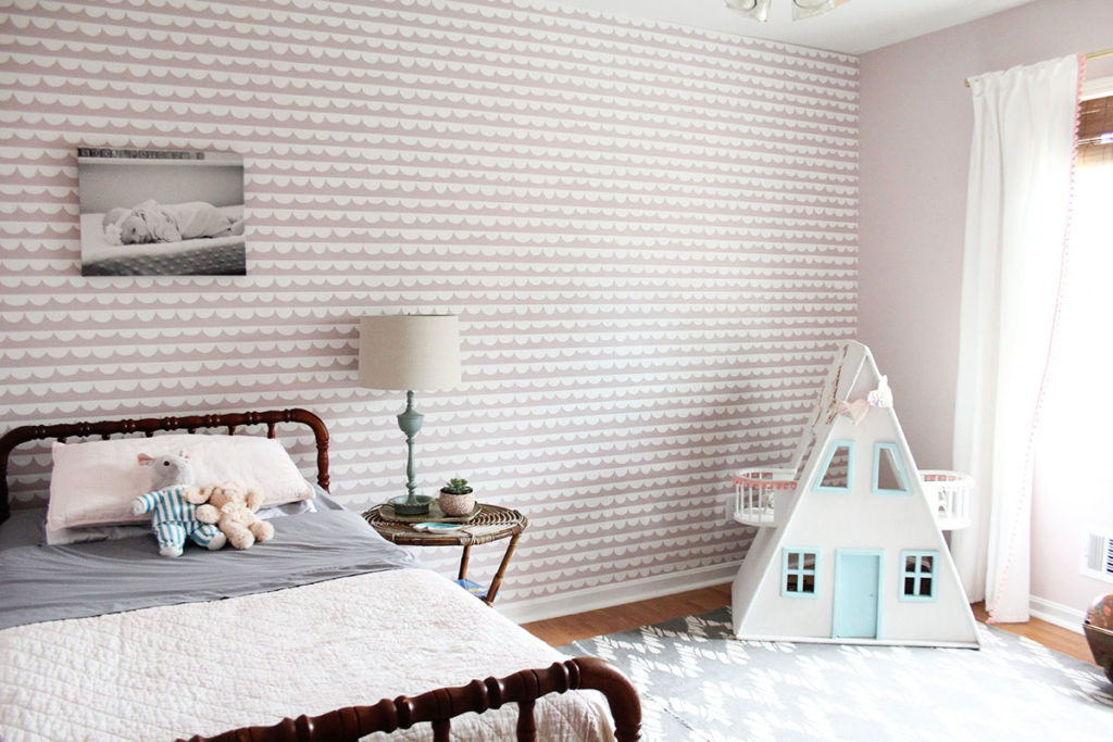 Pink wallpaper in a girls room with a Jenny Lind bed and custom dollhouse.