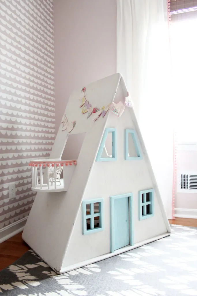 White and aqua wood dollhouse in front of pink wallpaper in a little girls bedroom - by Craftivity Designs