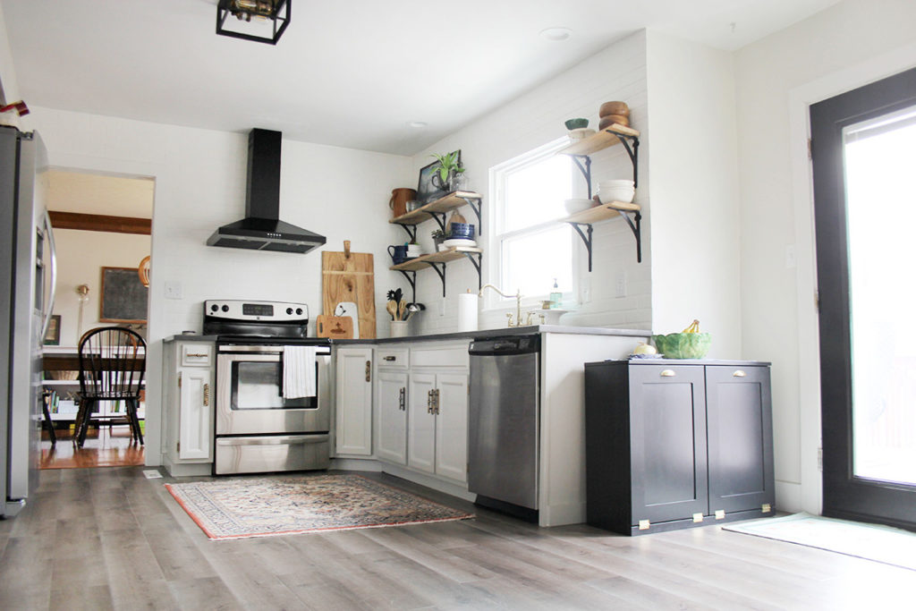 Budget kitchen remodel with gray painted cabinets, reclaimed wood shelves, and black range hood