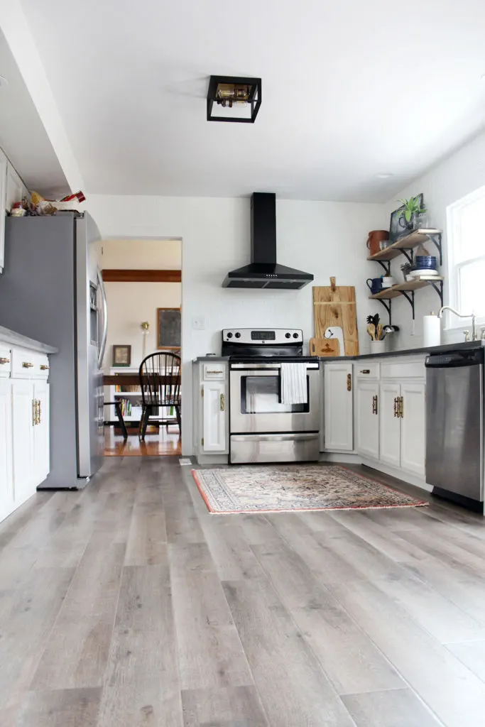 Budget kitchen remodel with gray painted cabinets, reclaimed wood shelves, and black range hood