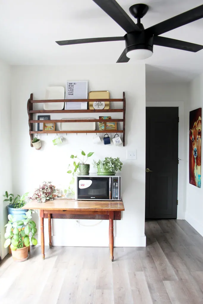 Microwave on an drop leaf table below a vintage plate rack