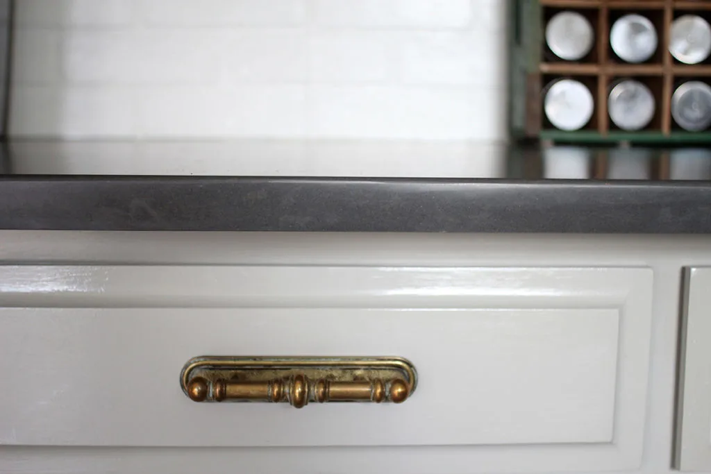 Kitchen Cabinets painted Mindful Gray with Black Quartz Counters and Antique Brass Hardware