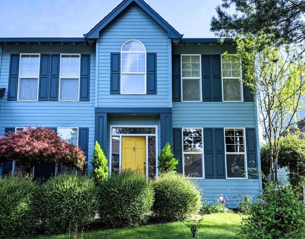 Yellow Front Door on Blue House with Lush Landscaping