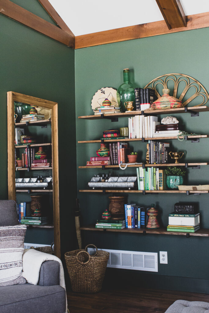 Global eclectic decor on shelves in green master bedroom