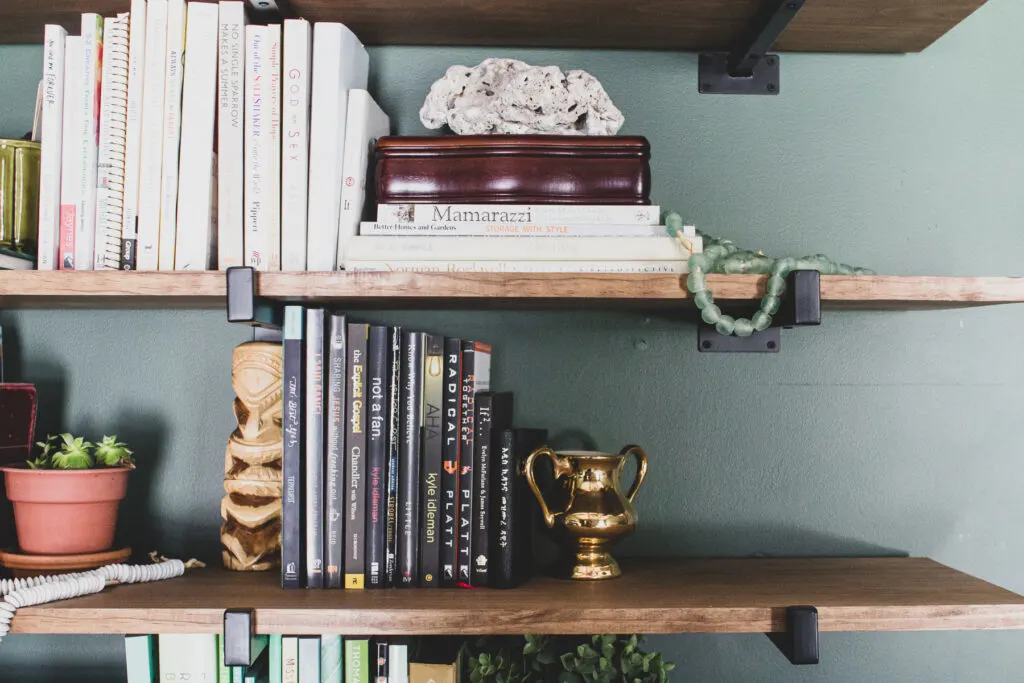 Global eclectic decor on shelves in green master bedroom