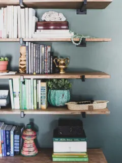 Global eclectic decor on heavy duty wall shelves for books in green master bedroom