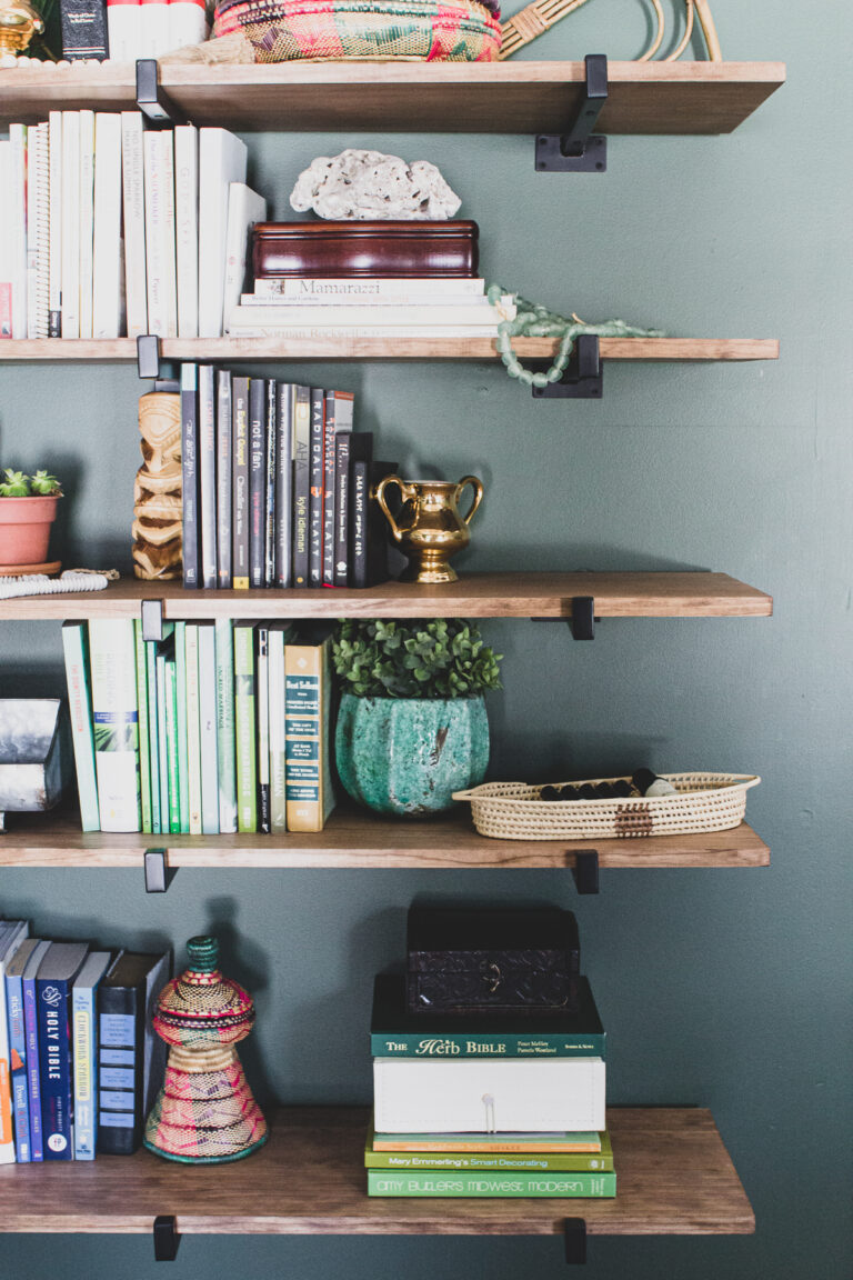 Global eclectic decor on heavy duty wall shelves for books in green master bedroom
