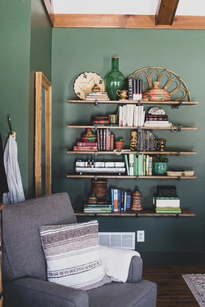 Global eclectic decor on shelves in green master bedroom