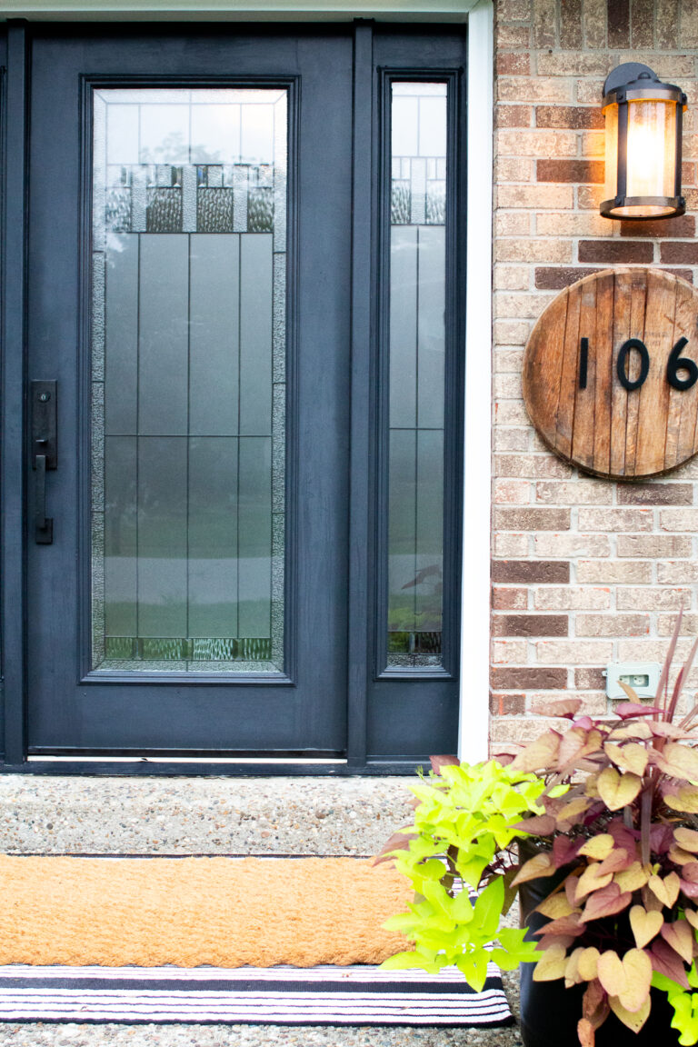small front porch with layered rugs and black door