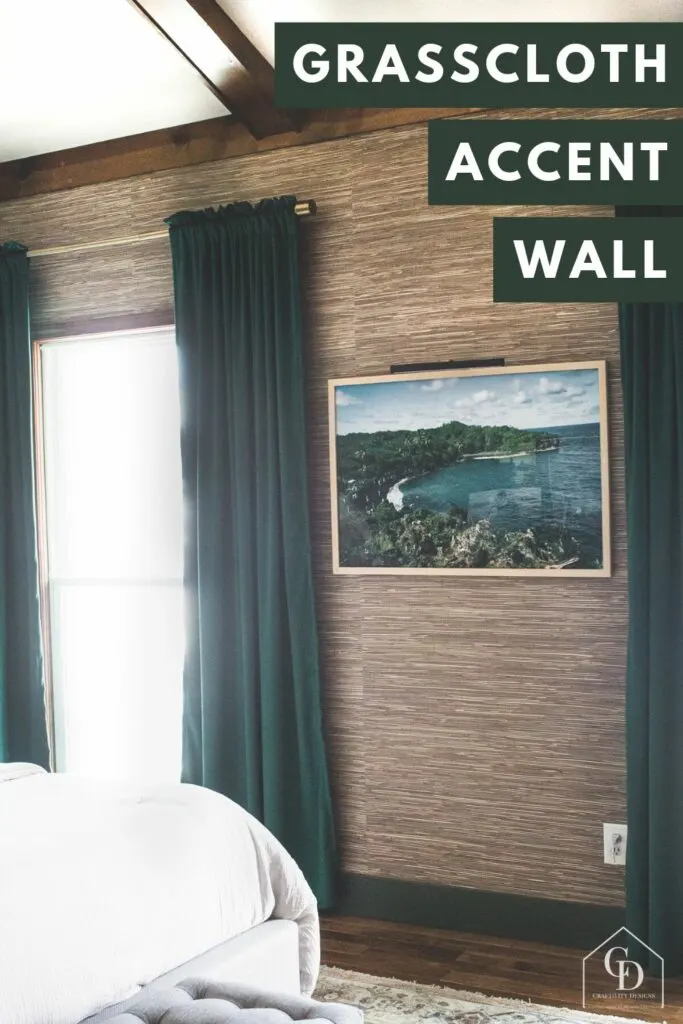grasscloth wallpaper accent wall in a master bedroom with green curtains, white bedding, wood beams, and beach art