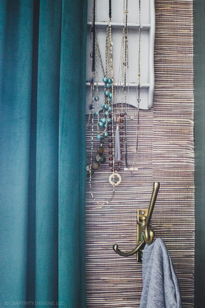 grasscloth wallpaper with green curtains, jewelry organizer, and coat hooks