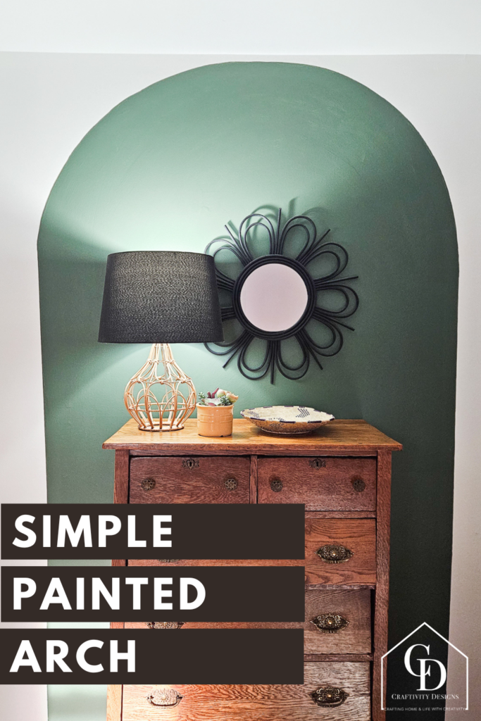 Dark green painted arch on a white wall. Antique dresser in front of arch, with a black mirror and lampshade. Text: Simple Painted Arch
