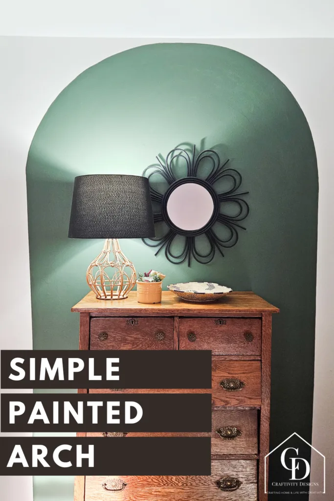 Dark green painted arch on a white wall. Antique dresser in front of arch, with a black mirror and lampshade. Text: Simple Painted Arch