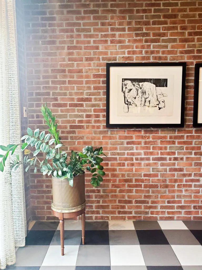 interior brick wall with black and white artwork, black and white check floor