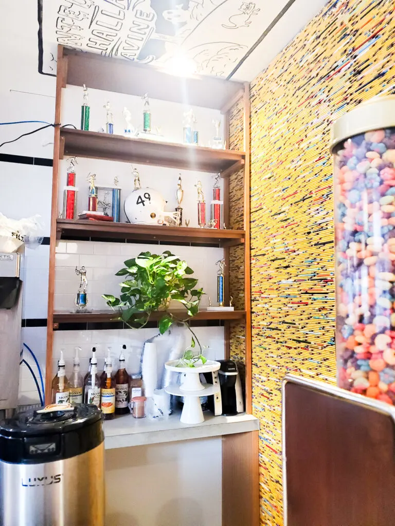 pencil covered wall, shelves filled with trophies and a football helmet, in poindexter coffee shop and cafe