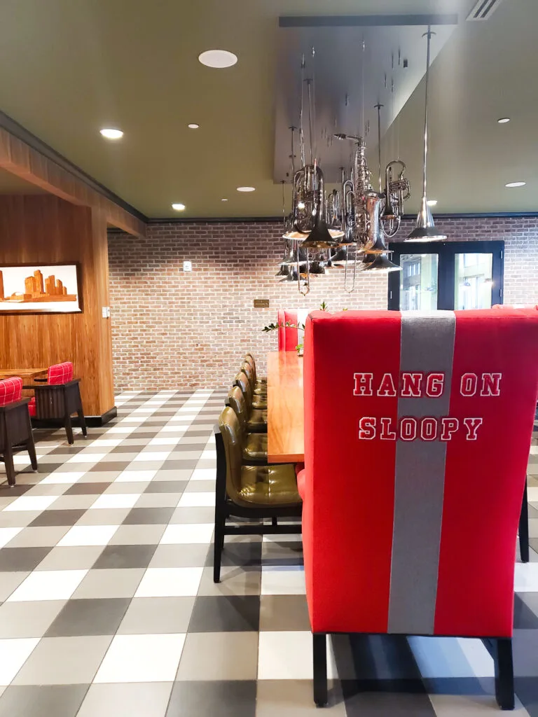 Red chair in Graduate Columbus lobby with song title "Hang on Sloopy" and a chandelier made iwth trumpets and trombones.